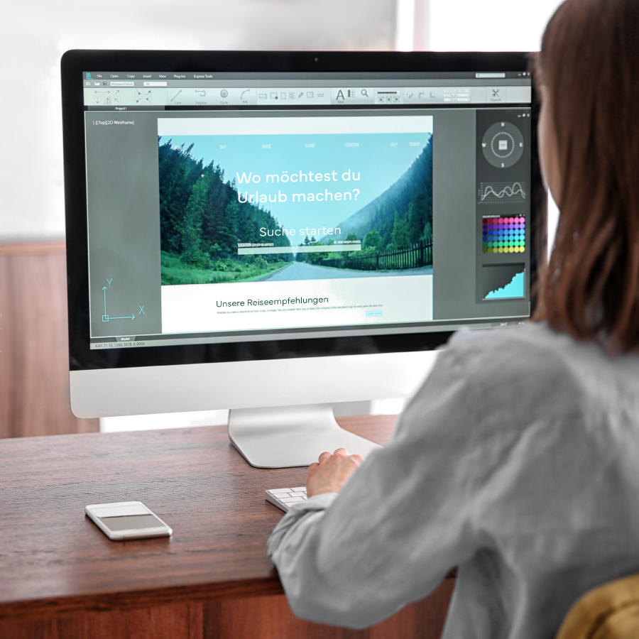 Frau sitzt am Schreibtisch und bearbeitet ein Layout mit einem Desktop-Publishing-Programm