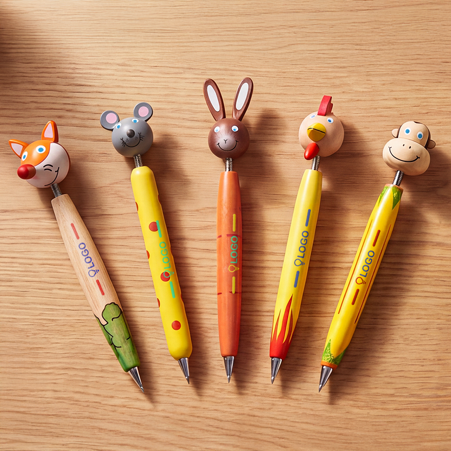 Verschiedene Holz-Kugelschreiber mit Tierkopf und individuellem Druck liegen nebeneinander auf einem Holztisch