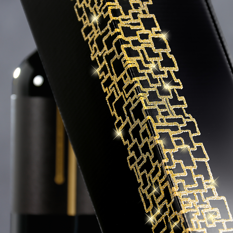 Goldene Details auf schwarzem Präsentkarton für eine Champagnerflasche