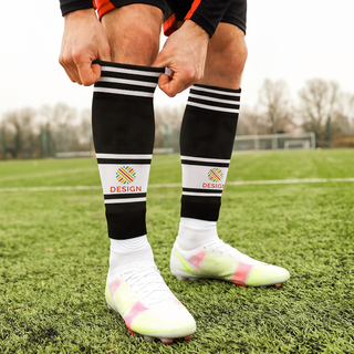 Person auf dem Fussballplatz trägt schwarze Stutzen mit individuellem Druck und weissen Streifen