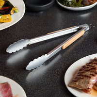 offene Grillzange auf Tisch zwischen Tellern